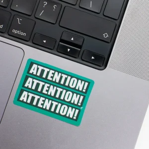 Vinyl Laptop Sticker irregular english text Attention shape with teal 3mm outline round corner and white text on macbook beside keyboard