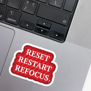 Vinyl Laptop Sticker irregular english text Reset restart refocus shape with white 3mm outline round corner and white text red background on macbook beside keyboard