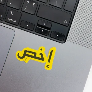 Vinyl Laptop Sticker irregular arabic text ekhs shape with yellow 3mm outline round corner and black text on macbook beside keyboard