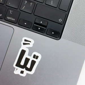 Vinyl Laptop Sticker irregular arabic text tabban shape with white 3mm outline round corner and black text on macbook beside keyboard