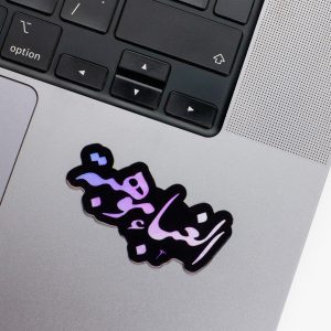Holographic Laptop Sticker irregular arabic text alghabaa mawheba shape with round corner with black text on macbook beside keyboard with inner fill shiny metallic rainbow effect
