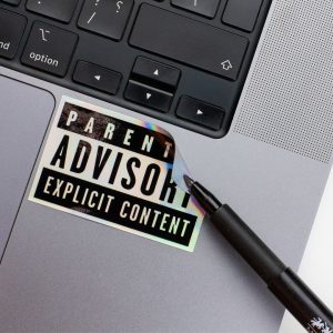 Holographic Laptop Sticker rectangle shape with round corner with black text Parental Advisory on macbook beside keyboard peeled off using a black marker with inner fill shiny metallic rainbow effect